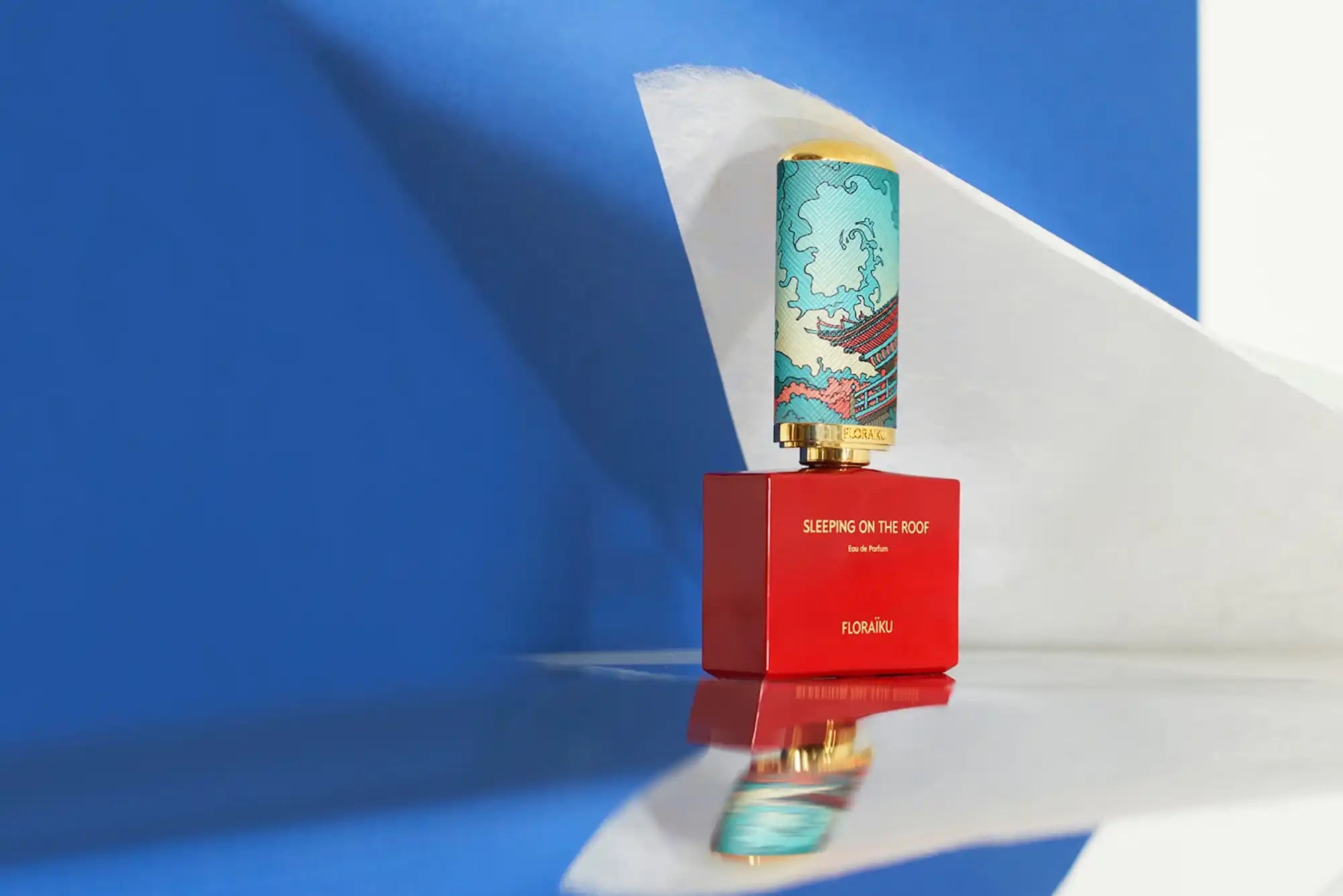 Turquoise beverage can balanced on a red box casting a shadow.